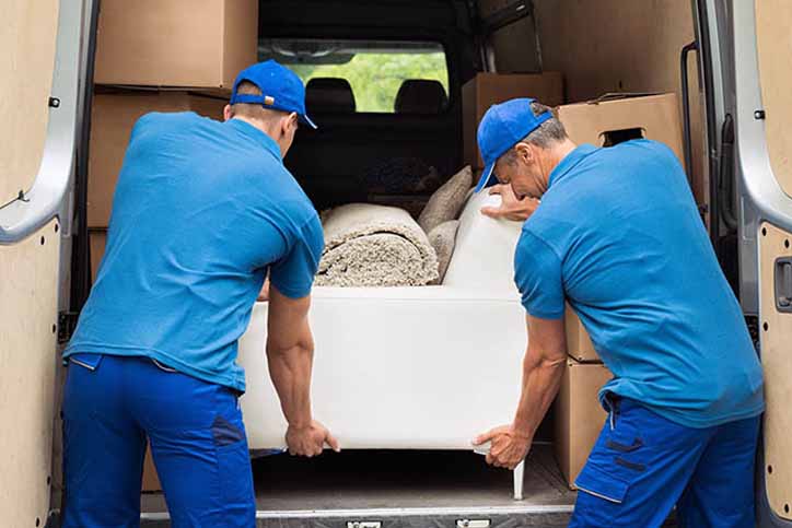 Movers Carrying Sofa Outside Truck On Street