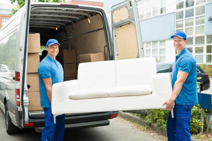 Movers Carrying Sofa Outside Truck On Street